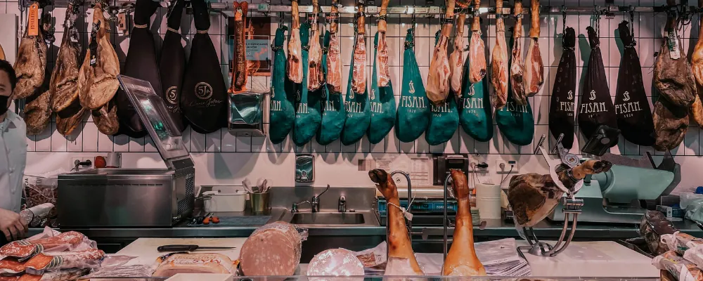 Obrador de charcutería con jamones colgados, cortadora y soportes jamoneros