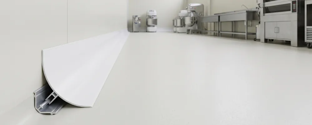 Perfil sanitario de PVC en la unión entre suelo y pared de una sala de procesado