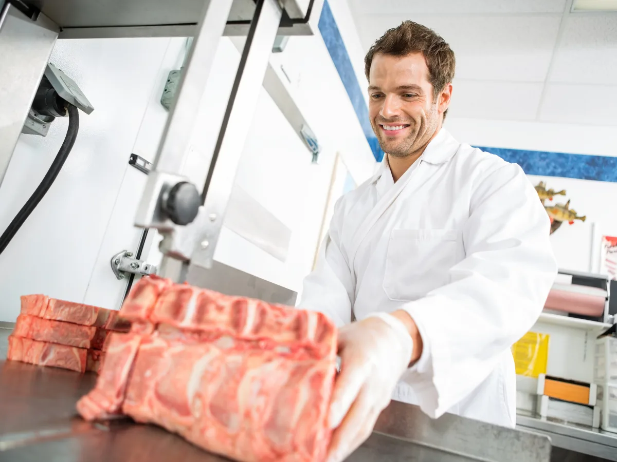 Carnicero cortando costillar con una sierra de cinta
